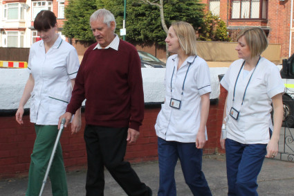 Patient walking up drive with early supported discharge team