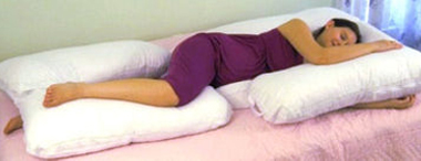 Lady laying on her side supported by pillows and cushios