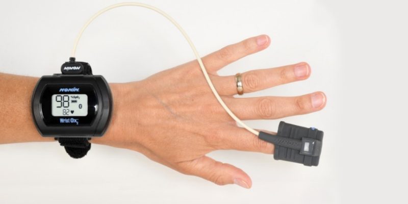 Image of a oximetry monitor placed around the wrist and a probe on the finger