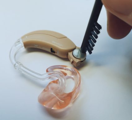 Cleaning brush magnet places battery into hearing aid correctly