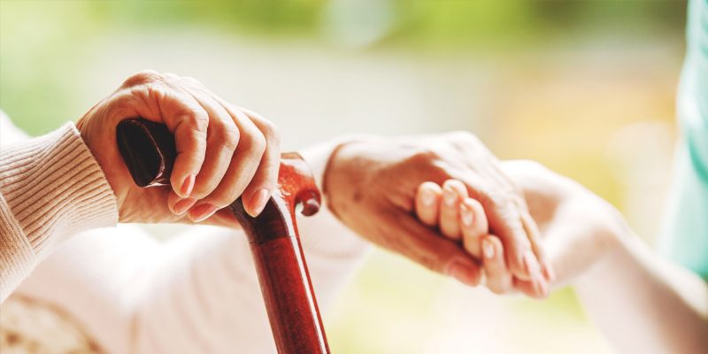 Photograph showing a carer holding a patients hand for help and support.