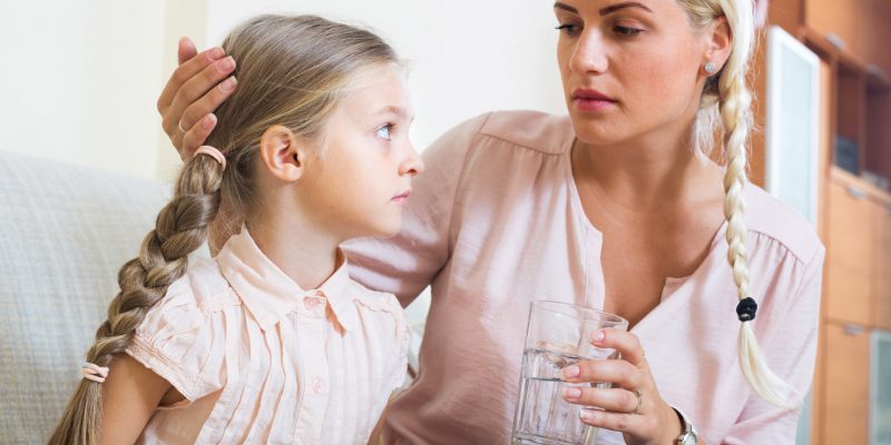 A mother encouraging her child to drink some water