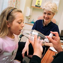 A child using an inhaler and spacer without a mask