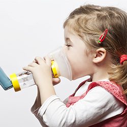A child using an inhaler and spacer with a mask