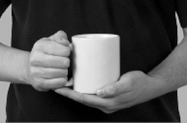 holding a cup with one hand and supporting the weight at the base  of the cup with the other