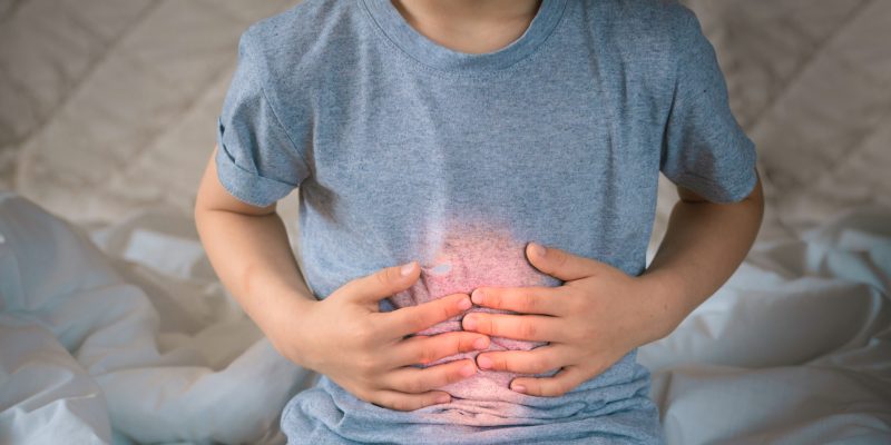 Child with hands on their stomach, the area has been highlighted in red to indicate pain