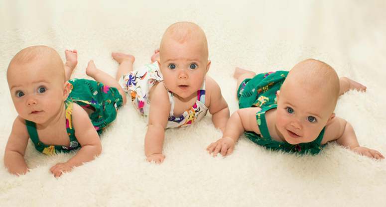 triplet girls, all laying on their tummies heads held up