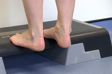 Slowly lower the heel below the level of the step