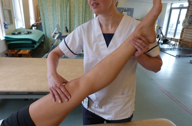 Leg raised and out straight, hand placed just above the top of the knee, the other hand under the ankle joint