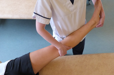 Leg raised and out straight, hand placed over the top of the knee supporting under the joint, the other hand under the heel