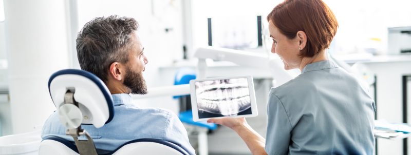 A dentist is showing their patient an X-ray of there teeth