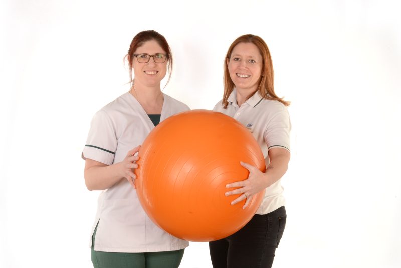 Two occupational therapists holding an exercise ball 