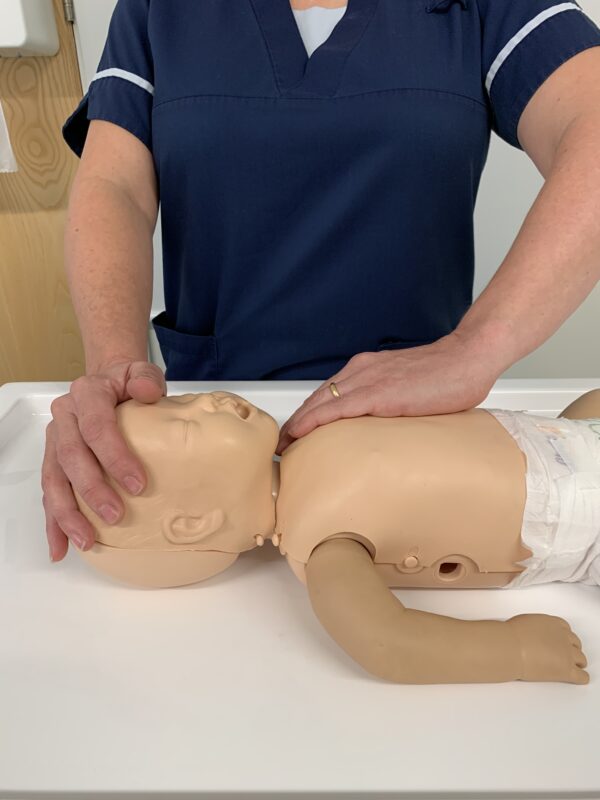 Demonstrating life support skills on baby mannequin - try to wake the baby.