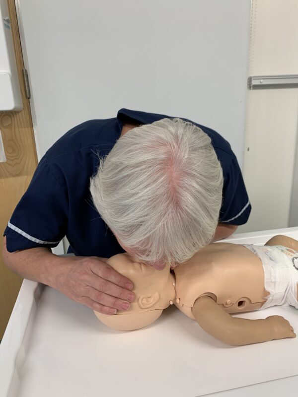 Demonstrating life support skills on baby mannequin - giving breaths