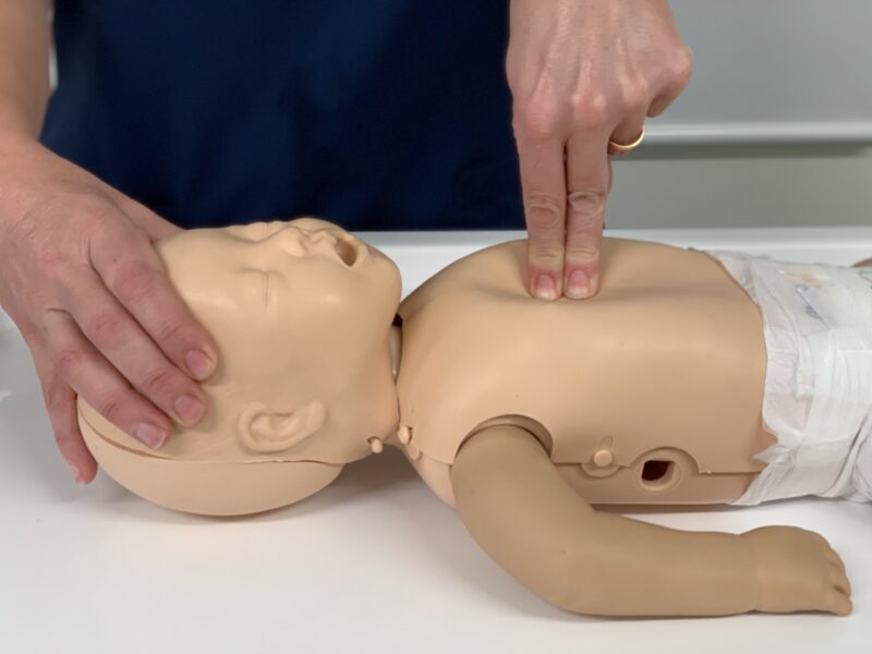 Demonstrating life support skills on baby mannequin - chest compressions with two fingers