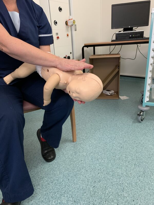Demonstrating life support skills on baby mannequin - back blows for choking