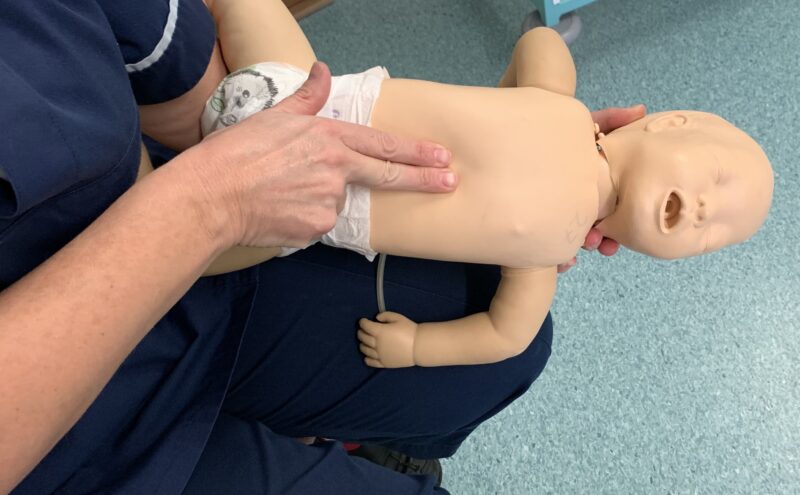 Demonstrating life support skills on baby mannequin - chest thrusts