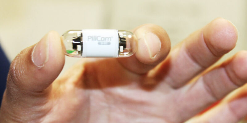 Pillcom capsule held between the finger and thumb