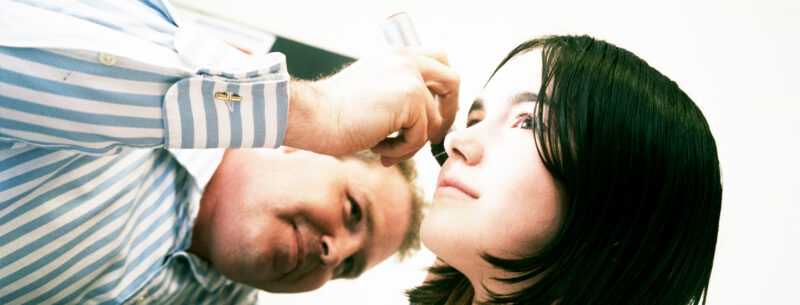 healthcare professional examining a young persons ear