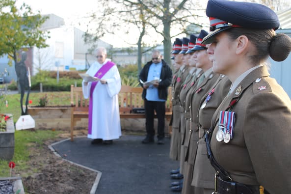 People gathering in a garden to pay their respects on Remembrance Day