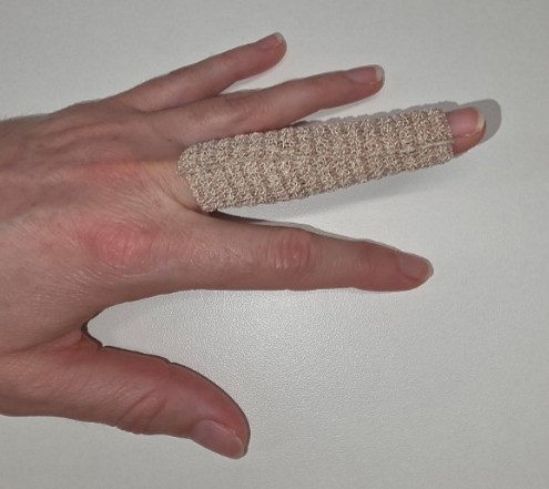 Picture of a finger covered in Coban bandaged by cutting the exact length and then wrapping it round.