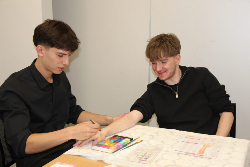 Two students participating in an anatomical body painting workshop