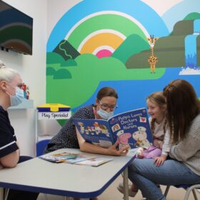 Young patient reading a book with staff at James Cook's pre assessment unit