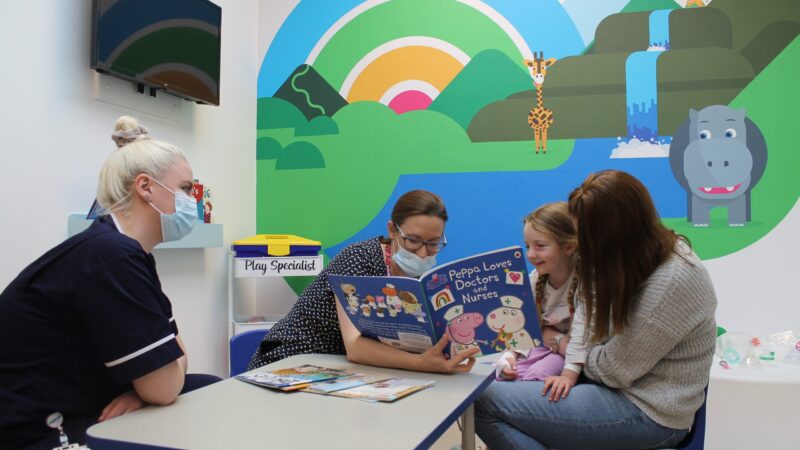 Young patient reading a book with staff at James Cook's pre assessment unit