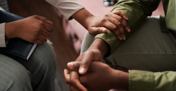 female psychologist keeping hand of wrist of male patient
