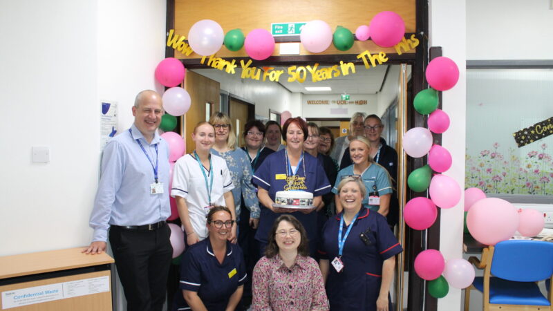 A group of people having their photo taken with a cake