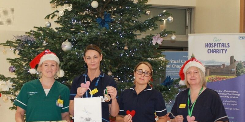 Group of people with baubles in front of a Christmas tree