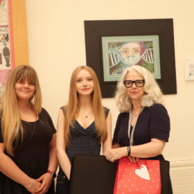 Lainey Garbutt (centre) receives her first place prize in front of her winning artwork.
