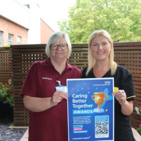 Two members of the volunteering team holding the CBT awards poster