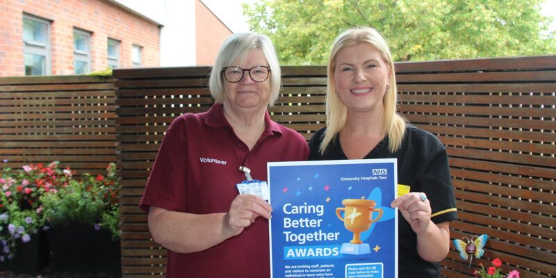 Two members of the volunteering team holding the CBT awards poster